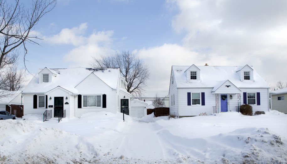 Two snowy houses on a suburban street after a snowfall.